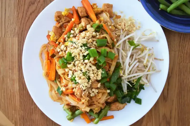 Pyszny pad thai oryginalny przepis z kurczakiem, warzywami i orzeszkami ziemnymi.