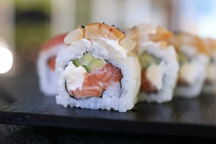 Uranaki z łososiem, kremowym serkiem i ogórkiem, zwieńczone krewetką. Pyszne danie sushi.