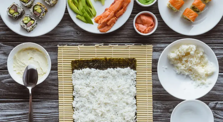 Idealny ryż do sushi jest kleisty i gotowy do zwinięcia z nori, łososiem i awokado.