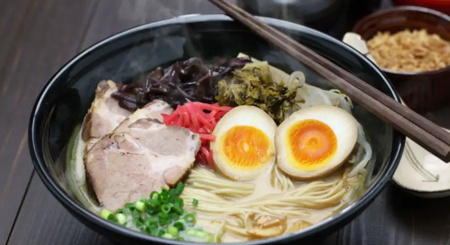 Parujący ramen z grubym makaronem, plastrami wieprzowiny, jajkiem na pół i szczypiorkiem. Idealny makaron do ramen to podstawa!