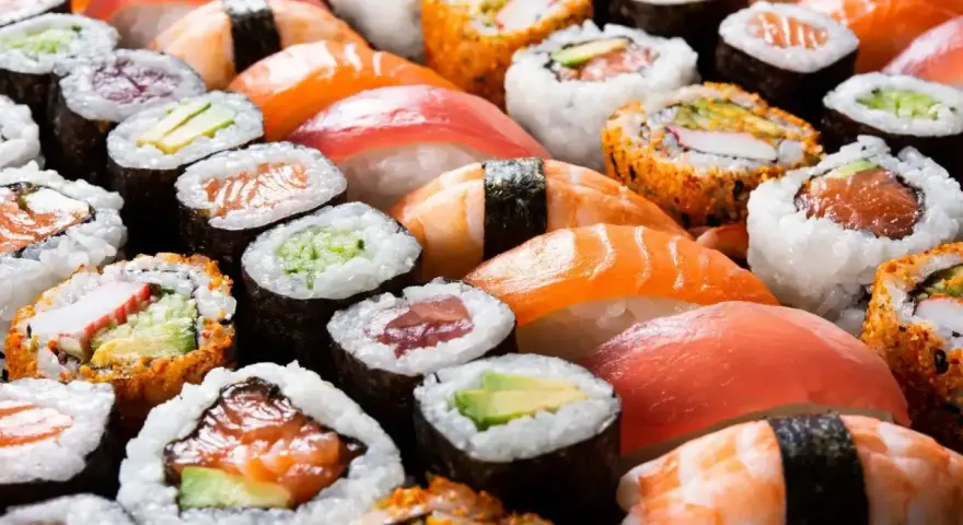 Różnorodne sushi, w tym rolki z łososiem i awokado, idealne dla dzieci. Czy dzieci mogą jeść sushi? Tak, jeśli wybierzemy łagodne składniki!