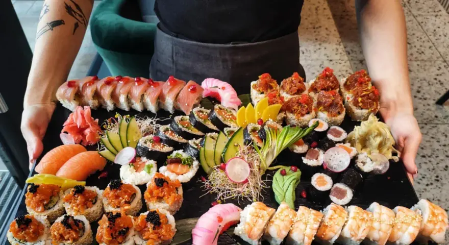 Taca pełna różnorodnego sushi: rolki z łososiem, tuńczykiem, krewetkami, a także nigiri. To właśnie sushi!