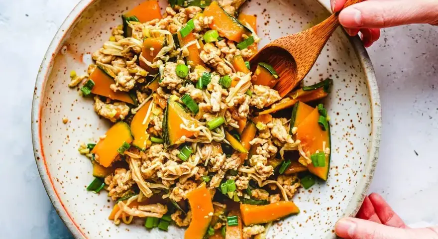 Mielone mięso z dynią i grzybami enoki, posypane szczypiorkiem. Danie wygląda jak składniki do tykwy sushi.