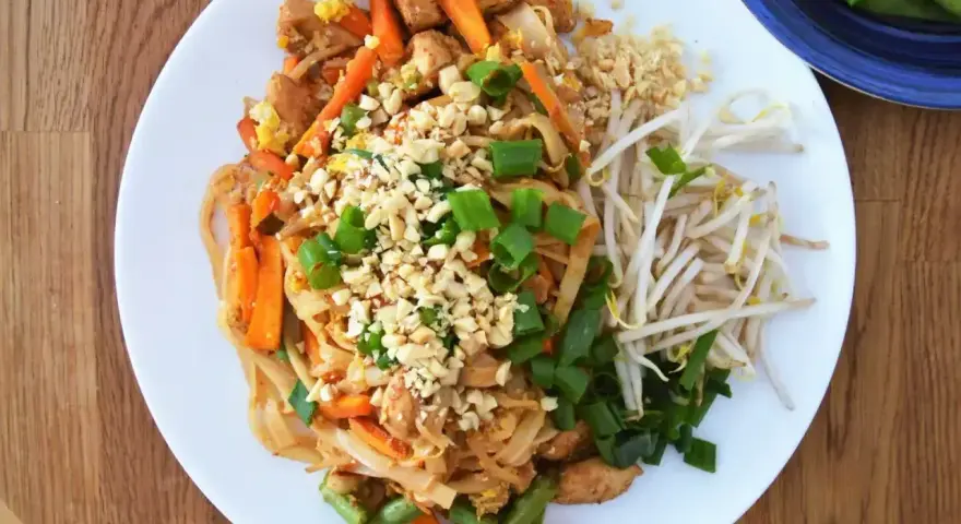 Pyszny pad thai oryginalny przepis z kurczakiem, warzywami i orzeszkami ziemnymi.