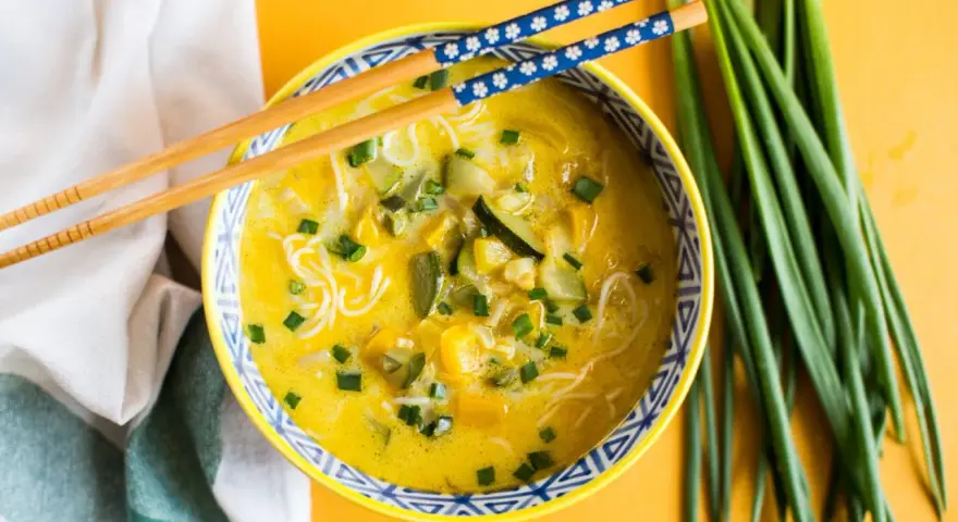 Aromaticzna zupa carry z makaronem ryżowym, warzywami i szczypiorkiem, gotowa do jedzenia pałeczkami.