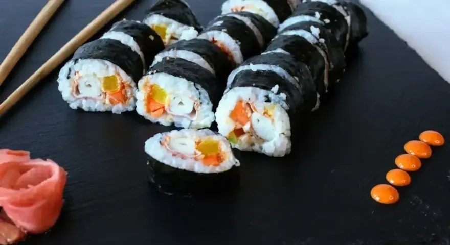 Rolka sushi philadelphia z łososiem, awokado i ogórkiem, podana z imbirem i wasabi.