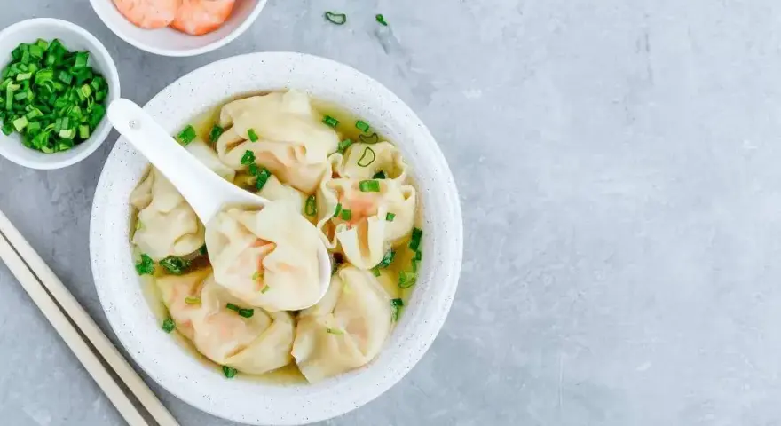 Aksamitna zupa won ton z krewetkami i szczypiorkiem, gotowa do zanurzenia się w jej smaku.
