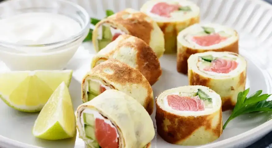 Sushi w naleśniku: rolki z łososiem, ogórkiem i serkiem, podane z dipem i limonką.