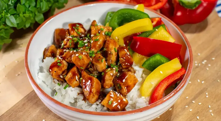 Pyszny kurczak z gotowym sosem teriyaki na ryżu, z kolorową papryką i szczypiorkiem.