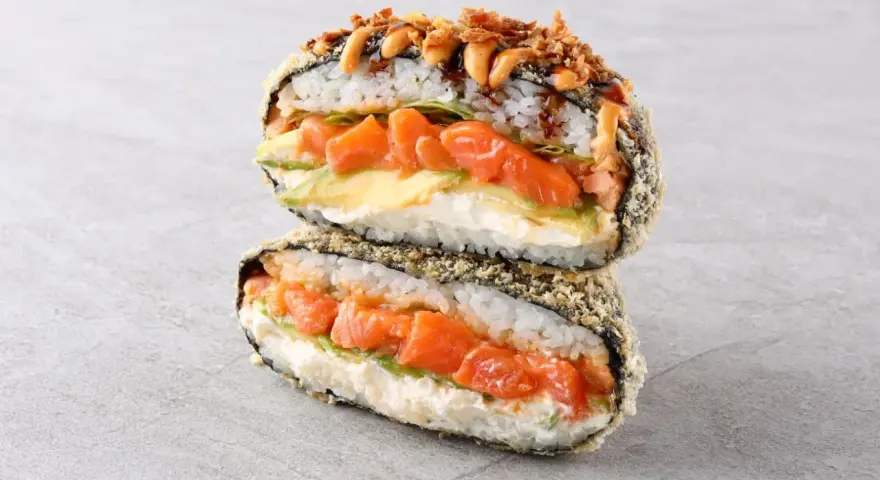 Sushiburger z łososiem, awokado i kremowym serkiem, otoczony chrupiącą panierką z ryżu i nori.