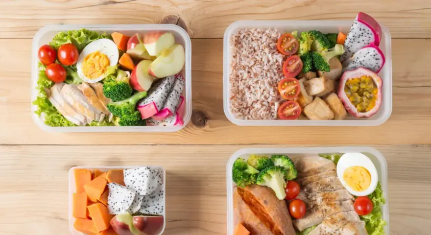 Cztery pudełka bento z kurczakiem, ryżem, warzywami i owocami. Idealne na zdrowy lunch, pokazują, bento co to jest.