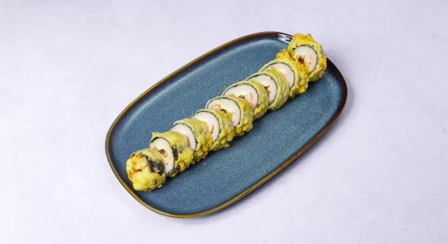Rząd chrupiących roladek sushi w cieście tempura, ułożonych na niebieskim talerzu.