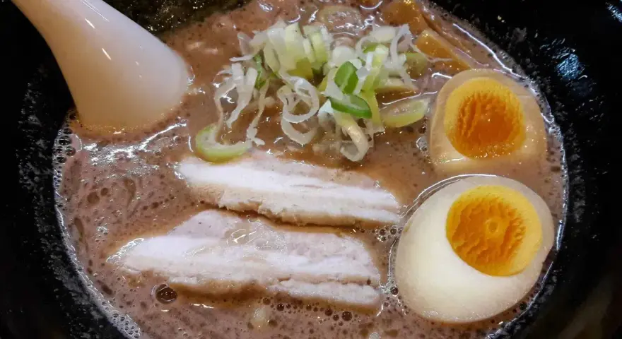Aksamitny bulion, dwa połówki jajka na miękko, plastry boczku i szczypiorek tworzą apetyczny ramen z boczkiem.