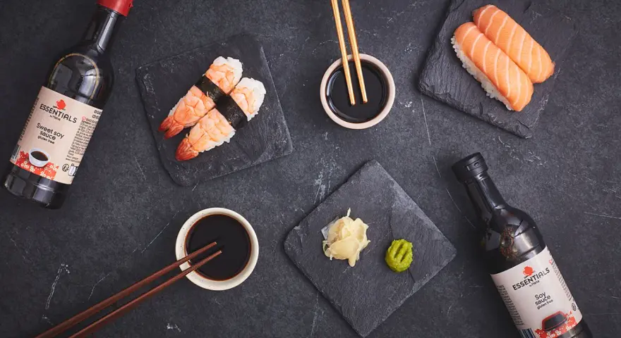 Słodki sos sojowy z butelki obok sushi z krewetkami i łososiem. Idealny dodatek do japońskich przysmaków.
