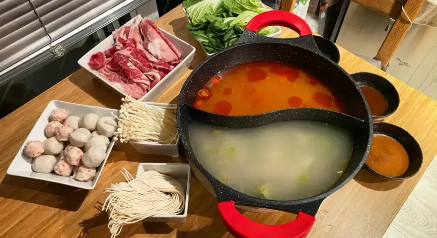 Pyszny **lau thai** z cienko pokrojonym mięsem, kluskami, grzybkami enoki, kulkami rybnymi i warzywami.