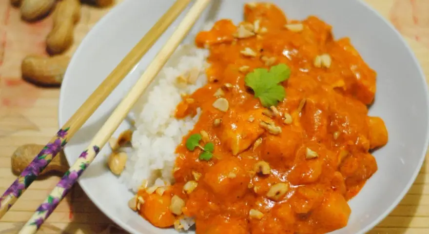 Pyszny massaman curry przepis: kurczak w kremowym sosie orzechowym z ryżem, posypany orzeszkami ziemnymi i kolendrą.