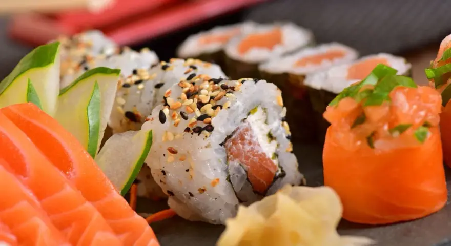 Pyszne sushi z łososiem, ogórkiem i sezamem. Choć ryby morskie zawierają zdrowe tłuszcze, warto pamiętać o umiarkowanym spożyciu, zwłaszcza jeśli dbamy o poziom cholesterolu.