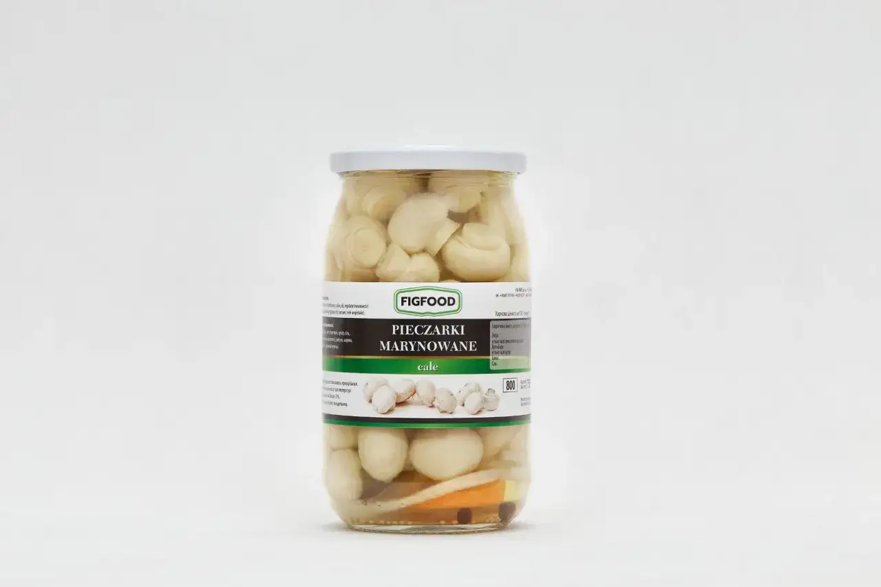 Słoik z pieczarkami marynowanymi marki Figfood, z widocznymi pieczarkami i przyprawami.