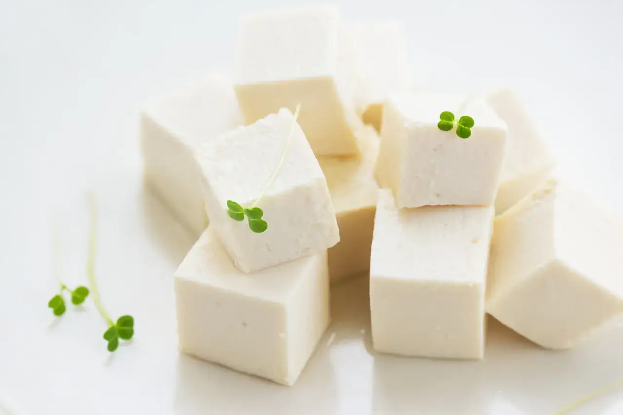 Kostki białego tofu, delikatnie ozdobione zielonymi kiełkami. To zdrowe i wszechstronne jedzenie, które można przygotować na wiele sposobów.