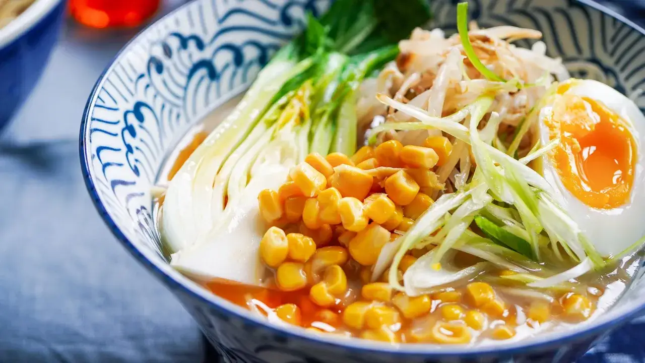 Miseczka aromatycznego ramen miso z jajkiem na pół, kukurydzą, kiełkami i pak choi. Pyszne danie, które rozgrzeje.