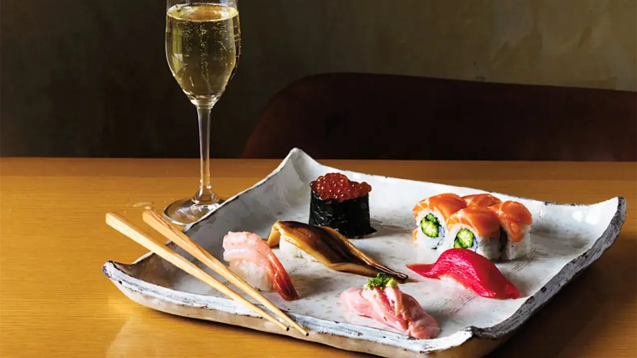 Eleganckie sushi z łososiem, krewetką i ikrą, podane z kieliszkiem musującego wina. Idealne pytanie: jakie wino do sushi?