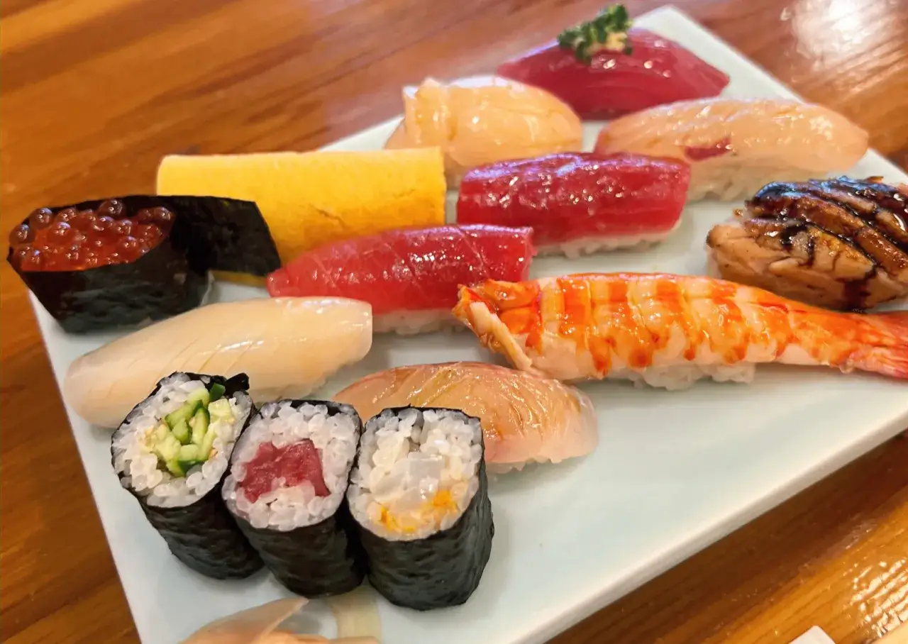 Talerz pełen różnorodnego sushi, od ikry łososia po krewetkę i makrelę, to prawdziwa uczta dla oczu i podniebienia. Smaki Japonii na talerzu.