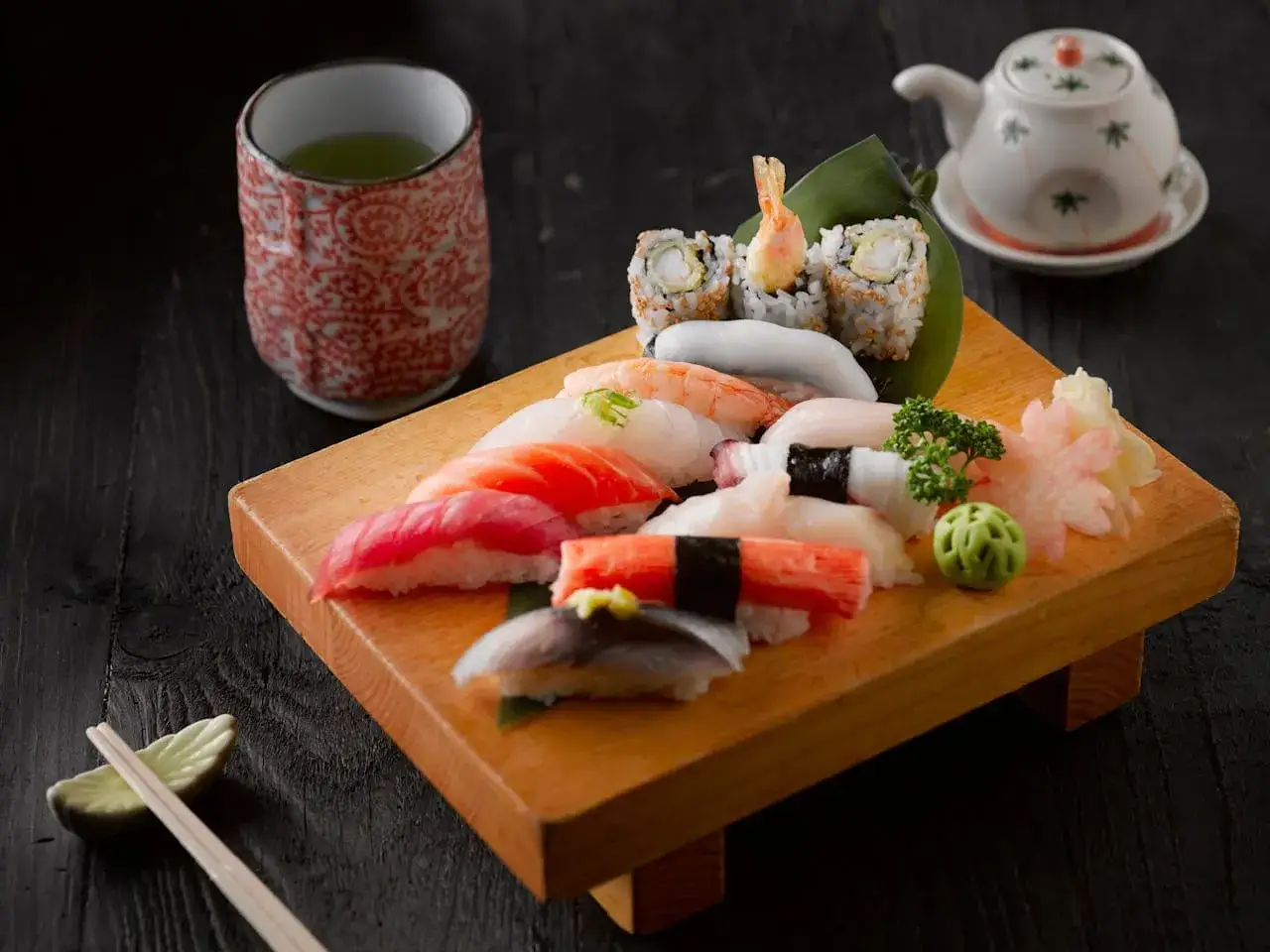 Zestaw sushi na drewnianej desce, z filiżanką zielonej herbaty i małym czajniczkiem. To danie, którego skąd pochodzi sushi, to prawdziwa uczta dla zmysłów.