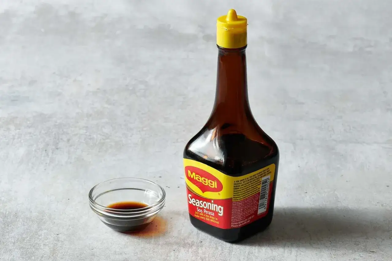 Butelka sosu sojowego Maggi i mała miseczka z ciemnym płynem. Idealny dodatek do każdej potrawy, by nadać jej głębi smaku.