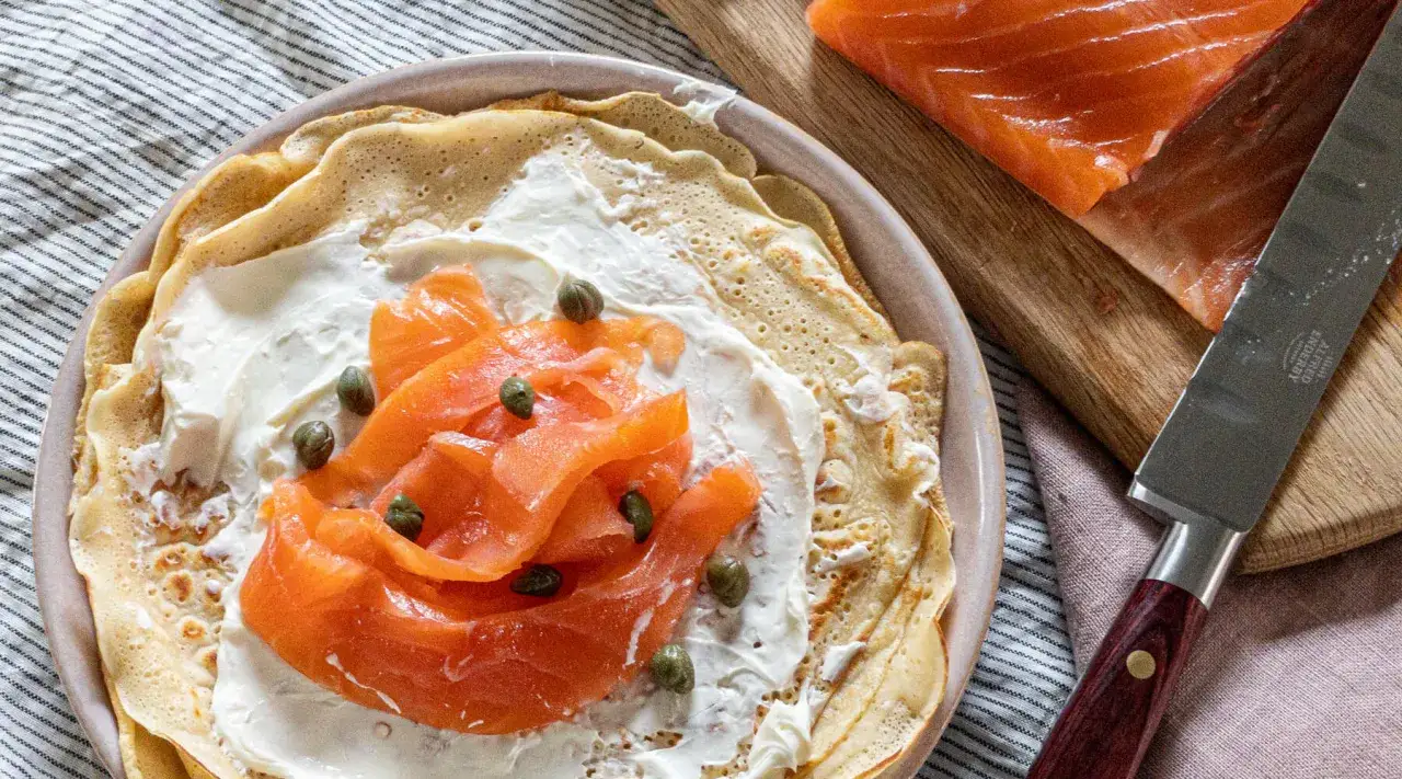 Naleśnik z wędzonym łososiem i serkiem, posypany kaparami. To pyszne sushi w naleśniku, które zachwyca smakiem.