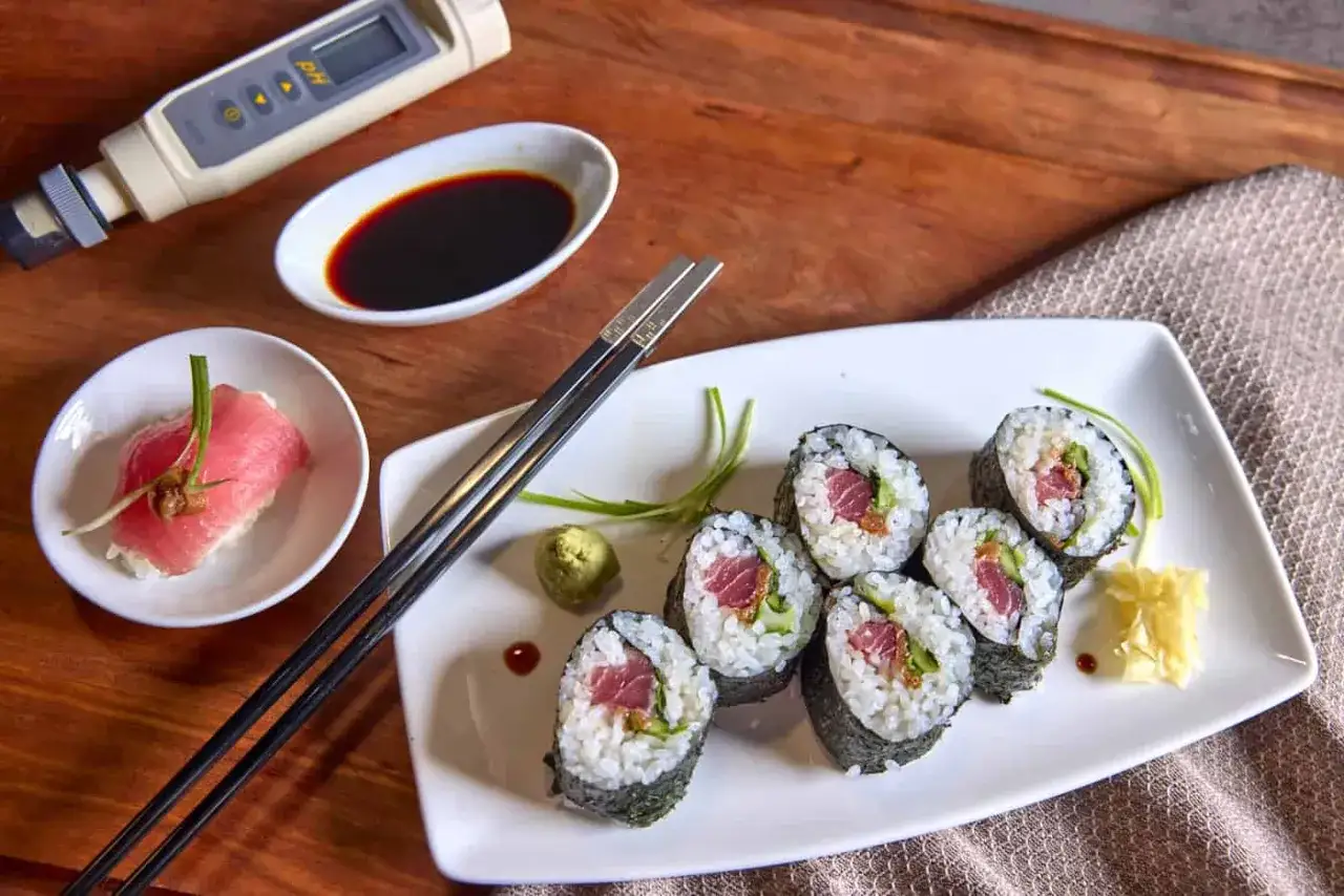 Na stole leży talerz z sushi, pałeczki i sos sojowy. Obok znajduje się dziwne urządzenie, które może pomóc ustalić, czy sushi się podgrzewa.