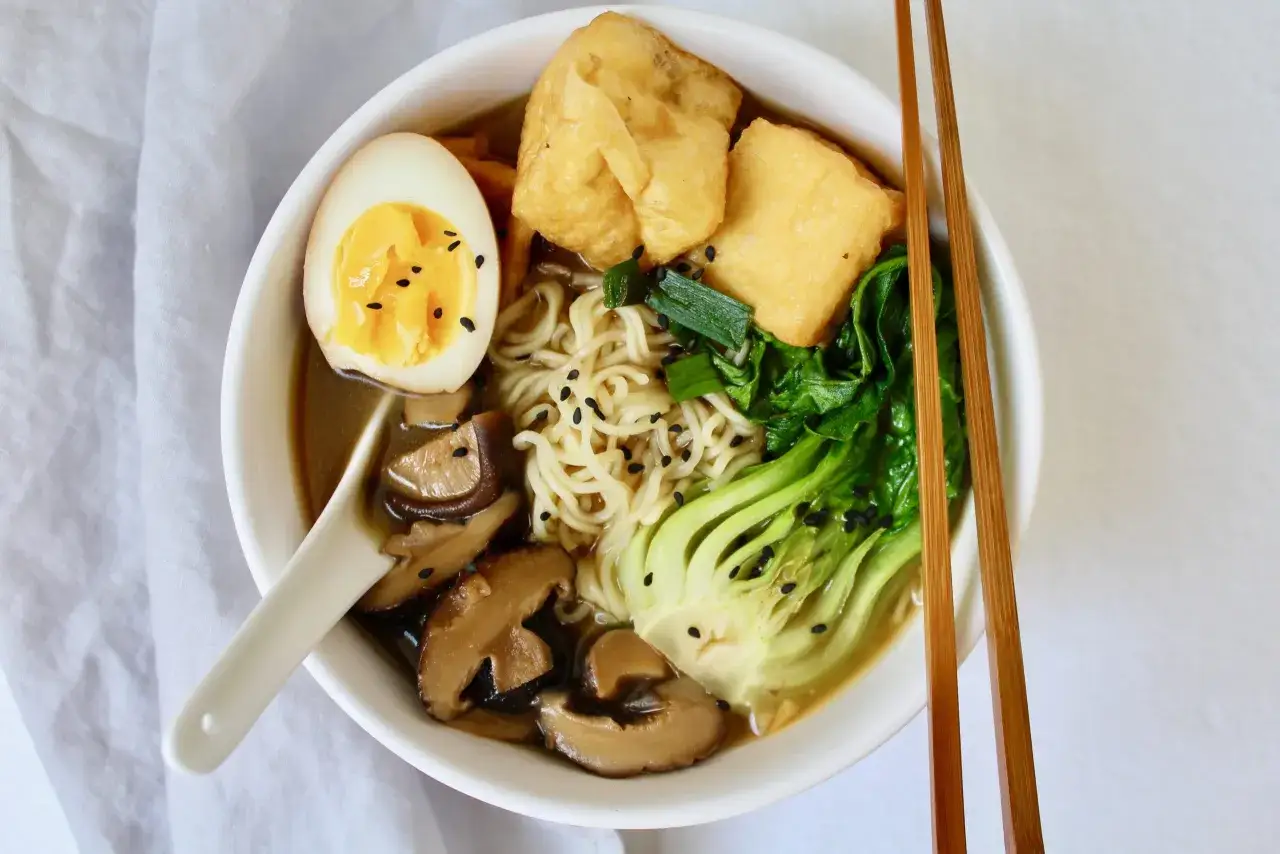 Miseczka ramenu z makaronem, jajkiem, pak choi, smażonym tofu i aromatycznymi grzybami do ramenu.