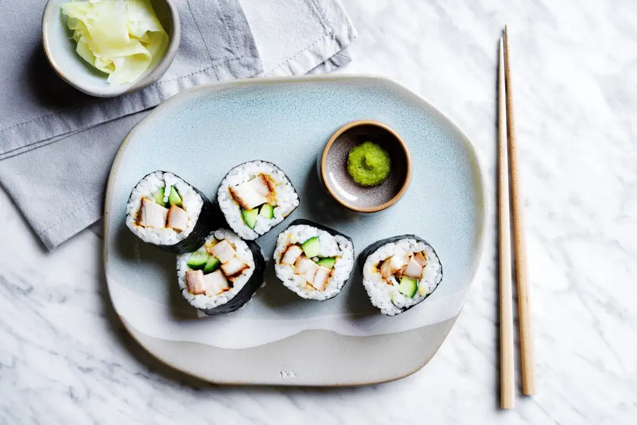 Roladki sushi z kurczakiem i ogórkiem, podane z wasabi i imbirem.