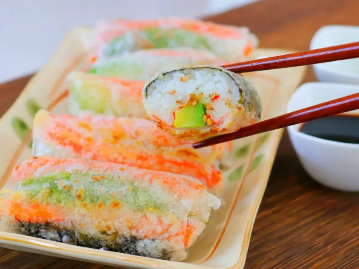 Kolorowe sushi w papierze ryżowym, z awokado i sezamem, podane z sosem sojowym.