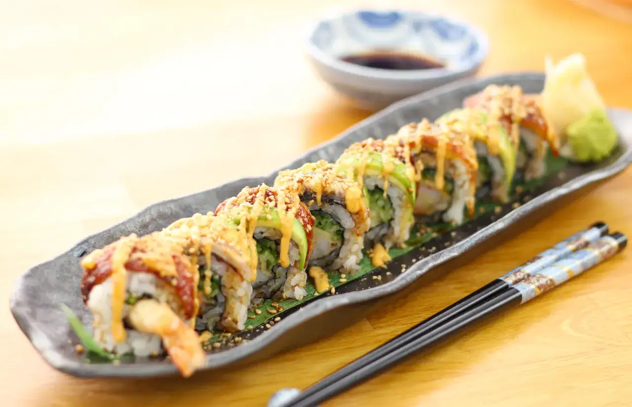 Wyśmienity dragon roll z awokado, krewetką i sosem, podany z wasabi i imbirem.