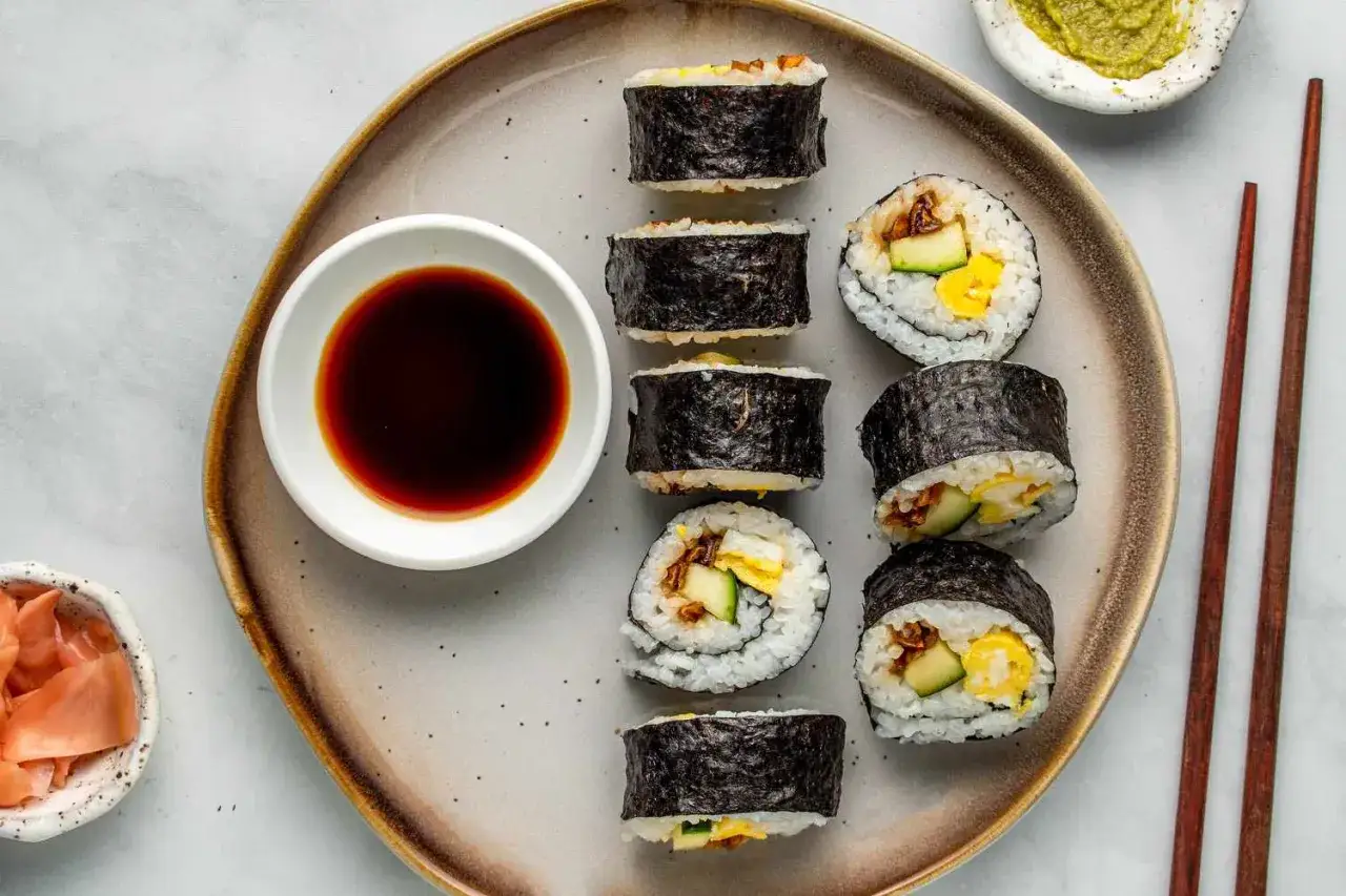 Pyszne futomaki tamago z jajkiem, ogórkiem i ryżem, podane z sosem sojowym i imbirem.