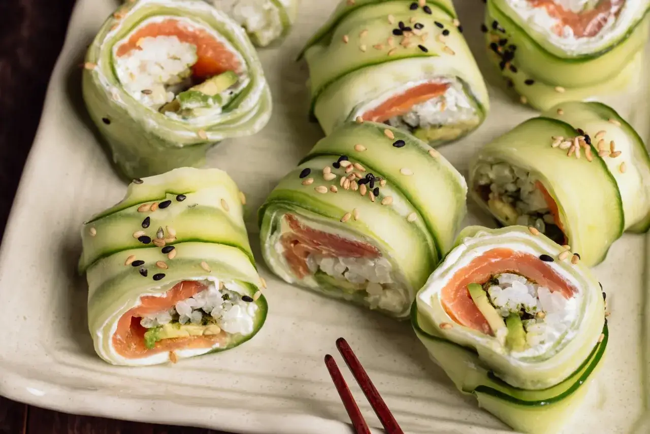 Roladki sushi z łososiem i awokado, zawinięte w ogórek, posypane sezamem. Zdrowe sushi, które nie podnosi cholesterolu.