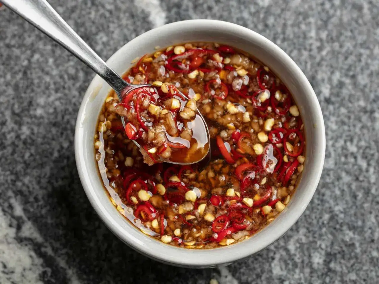 Łyżka nabiera aromatyczny sos tao tao z kawałkami chili i czosnku.