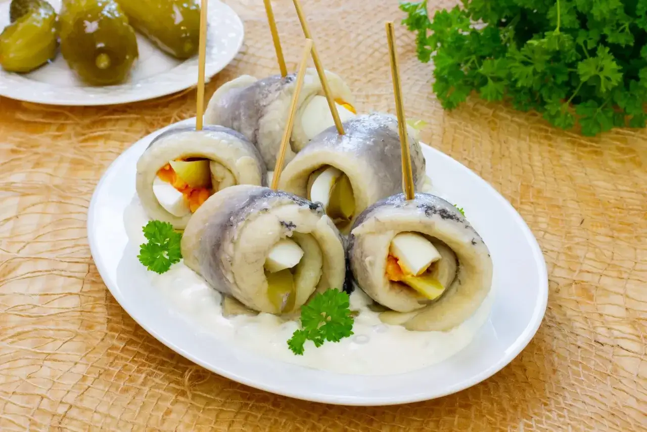 Roladki ze śledziem, jajkiem i ogórkiem, podane na sosie, wyglądają jak sushi.